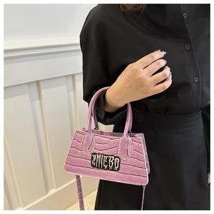 Detail of purple croc-effect mini bag featuring street style ZMIEBO logo patch and strap
