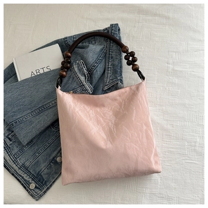 Detail of pink pleated velvet shoulder bag with unique wooden bead strap and gold zipper