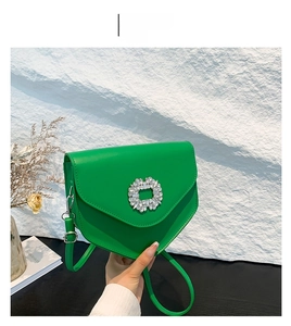 Détail du sac bandoulière vert avec boucle carrée en strass et sangle en cuir
