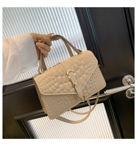Detail of beige crocodile pattern handbag featuring gold buckle and leather strap