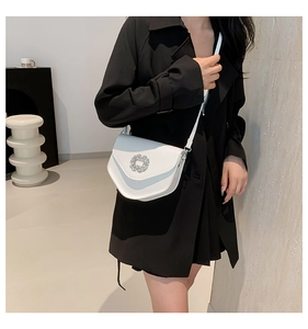 Vue détaillée d'un sac selle blanc semi-circulaire avec une boucle brillante en strass