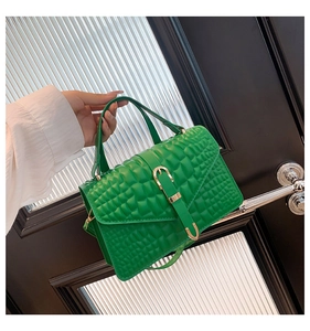 Detail of green faux leather handbag with crocodile pattern and golden buckle closure