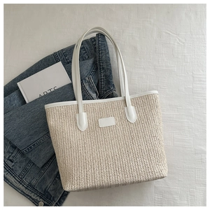 Detail of handwoven straw tote with white leather handles and a minimalist rectangular shape