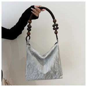Close-up of silver wrinkled fabric handbag with brown wooden bead circular handle
