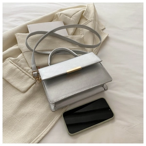 Detail of silver metallic handbag with gold bar clasp and smartphone for scale