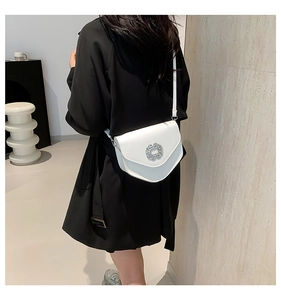 Détail d'un sac besace blanc en cuir avec une boucle florale en cristal de luxe raffiné