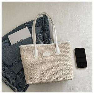 Detailed close-up of woven herringbone pattern and faux leather straps on straw tote bag