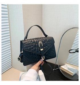 Detail of black crocodile texture handbag featuring elegant gold hardware and top handle