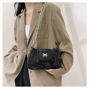 Détail de la boucle papillon argentée et du sac à chaîne noir à texture marbrée
