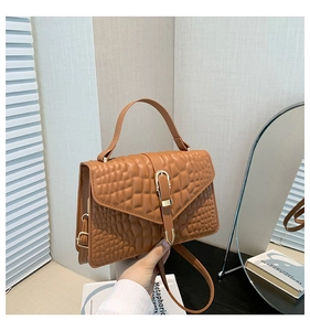 Detail of caramel brown crocodile embossed handbag with golden horseshoe buckle