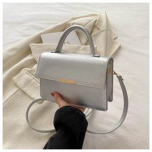 Close-up of silver mirror leather handbag with gold metal clasp and detachable strap