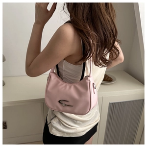 Rosafarbene Halbmond-Schultertasche mit Stern-Logo, getragen von einem Model zu Hause