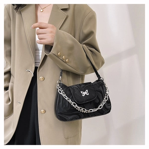 Detail of black crescent shoulder bag featuring silver butterfly clasp and metal chain