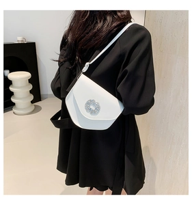 Gros plan d'un sac bandoulière en cuir blanc avec boucle métallique en strass brillant