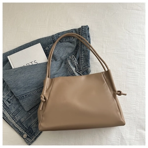 Vista dall'alto di una borsa tote in morbida pelle kaki con eleganti nodi su sfondo bianco