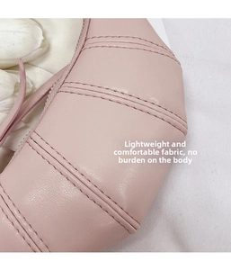Close-up of pale pink leather croissant bag showing soft pleated texture and fine stitching