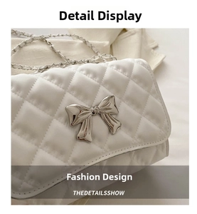 Detailed close-up of white quilted flap bag with silver bow accent and chain strap