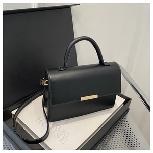 Minimalist black tote bag with gold metal buckle and detachable strap in a luxury box