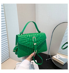 Detailed view of green crocodile embossed handbag with golden horseshoe buckle