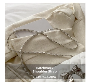 Detail of white quilted bag with spliced metal chain strap and bow-knot clasp