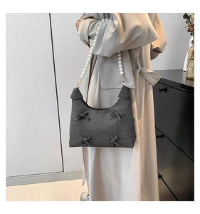 Close-up of stylish grey denim tote bag with handmade bows and pearl beaded handle