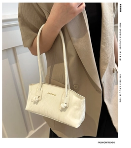 Gros plan du sac à bandoulière beige montrant le cuir synthétique texturé et le détail du nœud