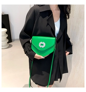 Détail du sac bandoulière en cuir vert vif avec boucle florale en strass étincelants