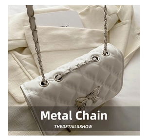 Detail view of silver metal eyelets and leather-woven chain strap on a white quilted bag