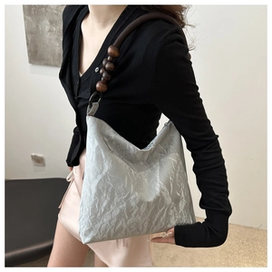 Detail of silver pleated fabric bag with retro dark brown wooden bead shoulder strap