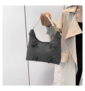Detail of grey fabric tote bag with bow accents and large faux pearl beaded handle