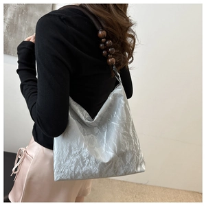 Detailed view of silver velvet tote bag with brown wooden bead shoulder strap