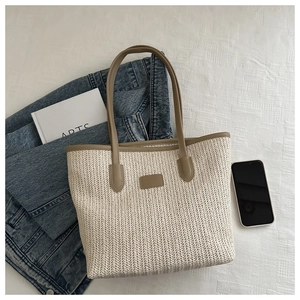 Flat lay of a beige woven tote bag with brown leather handles and lifestyle accessories