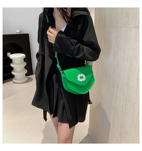 Détail d'un sac à bandoulière vert vif avec une boucle carrée en strass et sa bandoulière