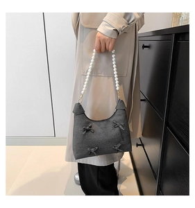Detail of grey denim tote bag with oversized pearl handle and 3D bow embellishments