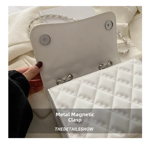 Detailed close-up of the silver magnetic clasps and quilted texture of the white bag