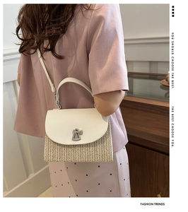 Detail of a woven straw crossbody bag with white leather flap and silver metal lock closure