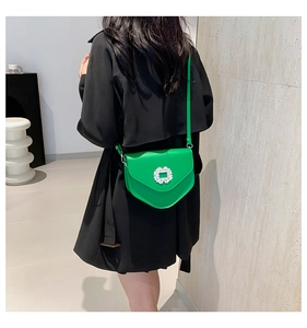 Détail d'un sac à bandoulière vert vif doté d'une boucle en strass étincelante sur le rabat