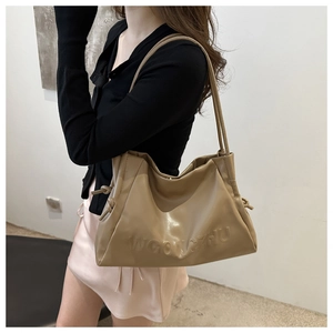 Dettaglio borsa hobo in morbida pelle beige con logo in rilievo e sottili spalline