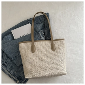Close-up of beige woven tote bag texture with brown leather straps on casual denim