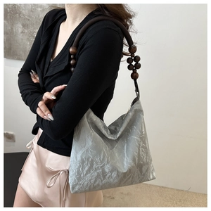 Detail of silver pleated hobo bag with distinctive brown wooden bead handle straps