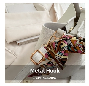 Detail of white lychee grain leather bag with gold hardware and colorful silk scarf