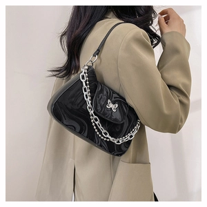Détail du sac à bandoulière noir marbré avec boucle papillon et chaînes argentées