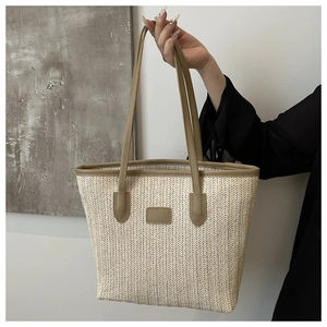 Detailed macro view of the cream woven texture and brown leather trim on a tote bag