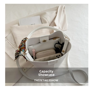Internal capacity of white bucket bag showing phone, wallet, lipstick and sunglasses