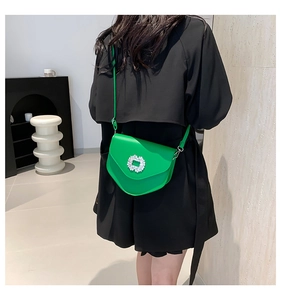 Détail d'un petit sac bandoulière vert vif avec boucle en strass et bandoulière en cuir fin