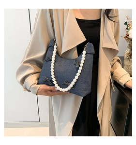 Detail of denim shoulder bag featuring 3D bows and decorative pearl handle