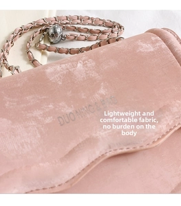 Close-up of pink velvet crossbody bag with silver chain and adjustable metal ball