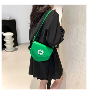 Détail du sac bandoulière vert vif avec boucle en cristal carré porté par un mannequin