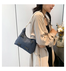 Detail of dark blue denim tote with 3D bows and elegant white faux pearl handle