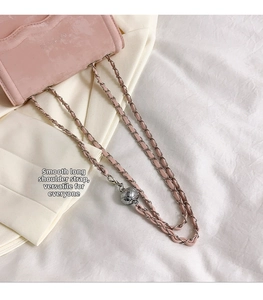 Detail of pink crossbody bag showing silver adjustable metal ball and leather chain strap